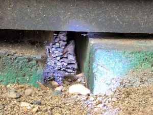 A foundation corner with slate debris and a gap, documented by Sasquatch Pest Control.